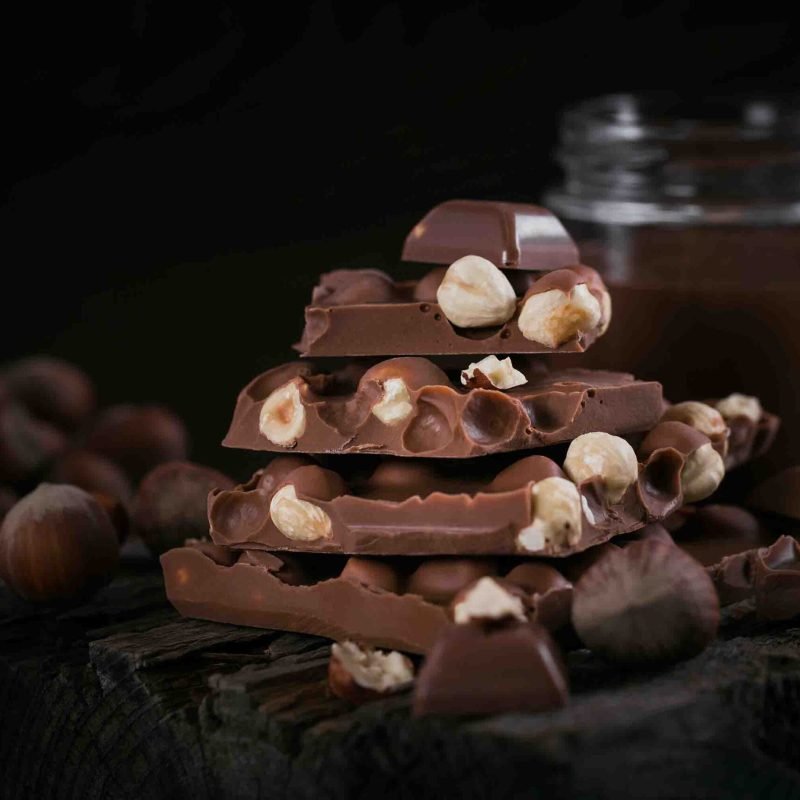 pile-of-hazelnut-milk-chocolate-and-nuts-on-dark-b-2023-11-27-05-01-44-utc